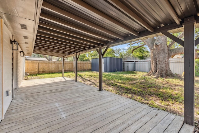 wooden deck with a fenced backyard, an outdoor structure, and a storage unit