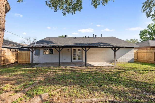 rear view of property with a fenced backyard, french doors, a yard, and brick siding