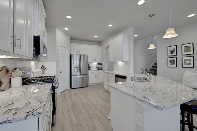 kitchen featuring appliances with stainless steel finishes, a sink, a breakfast bar, white cabinetry, and recessed lighting