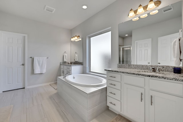 bathroom featuring a shower stall, a garden tub, two vanities, and recessed lighting