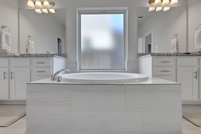 bathroom featuring tile patterned floors, a garden tub, and vanity