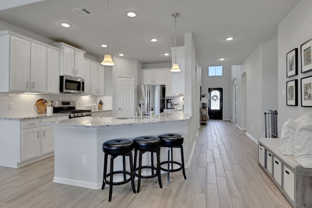 kitchen featuring stainless steel appliances, a sink, a kitchen breakfast bar, recessed lighting, and light wood-style flooring