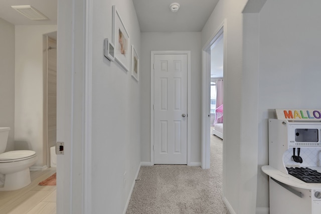 hall featuring baseboards and light carpet