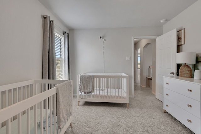 bedroom with arched walkways and light colored carpet