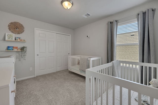 bedroom with a closet, carpet flooring, baseboards, and a crib