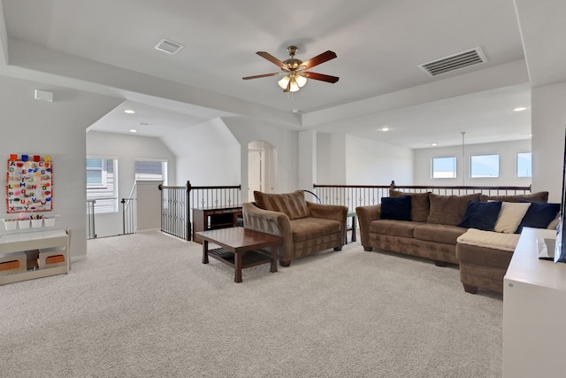 carpeted living area with ceiling fan, recessed lighting, a tray ceiling, and arched walkways