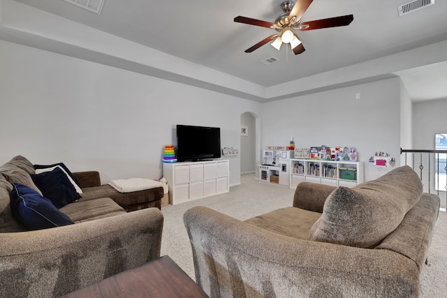 carpeted living area with arched walkways and ceiling fan