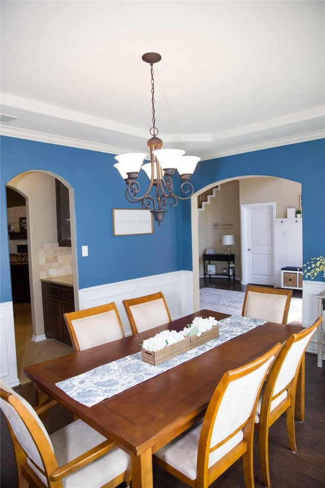 dining area featuring an inviting chandelier, arched walkways, visible vents, and ornamental molding