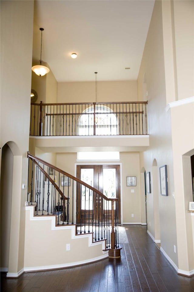 entryway featuring arched walkways, an inviting chandelier, hardwood / wood-style floors, and a towering ceiling