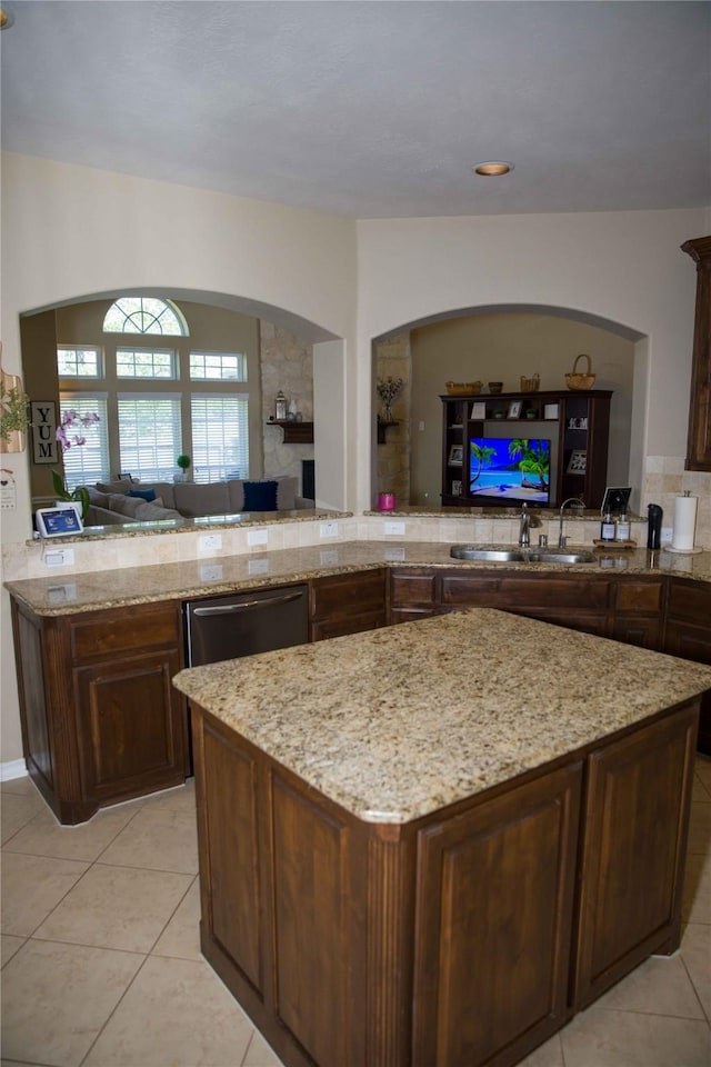 kitchen featuring light stone counters, open floor plan, light tile patterned floors, and dishwasher
