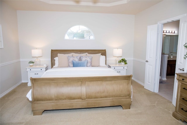 bedroom with light colored carpet, baseboards, and ensuite bathroom