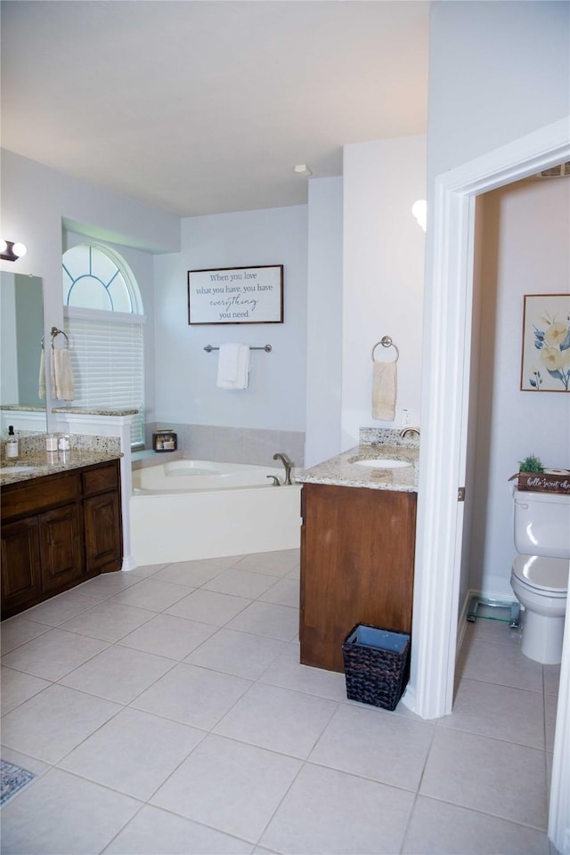full bath with a garden tub, toilet, tile patterned floors, two vanities, and a sink