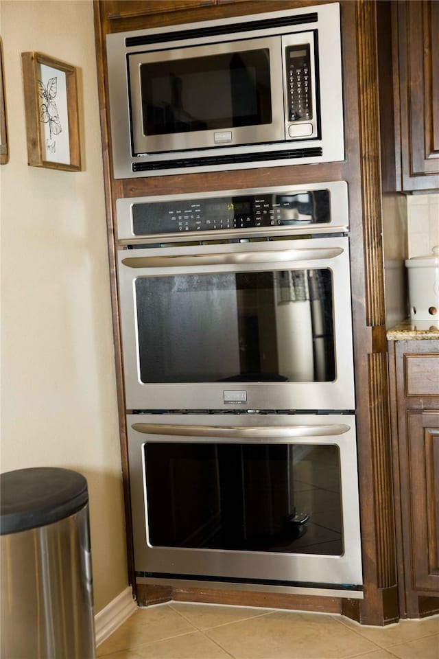 kitchen featuring baseboards, light countertops, appliances with stainless steel finishes, and light tile patterned flooring