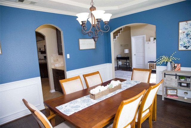 dining area with arched walkways, an inviting chandelier, visible vents, and a wainscoted wall