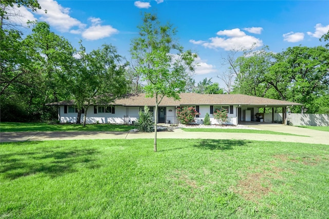 ranch-style home featuring an attached carport, concrete driveway, fence, and a front lawn