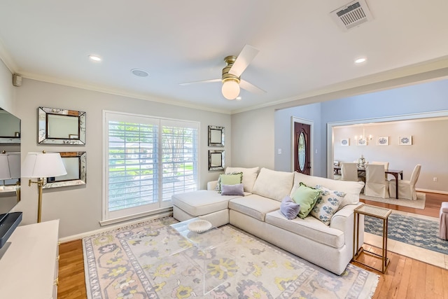 living room with baseboards, ornamental molding, visible vents, ceiling fan, and wood finished floors