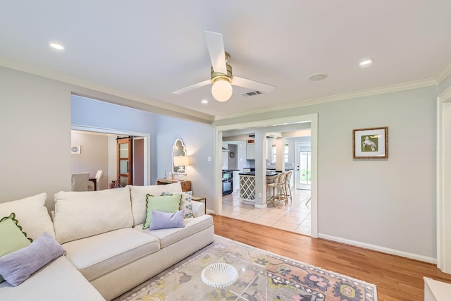 living area with light wood-style floors, ceiling fan, ornamental molding, visible vents, and baseboards