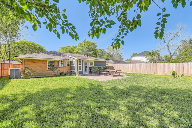 rear view of house with a yard, a patio, a fenced backyard, and central AC