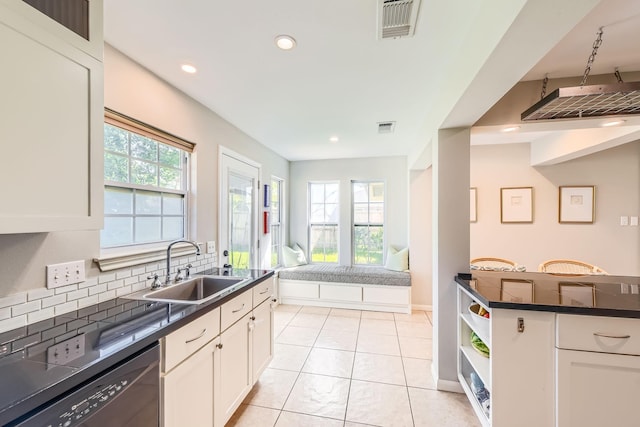 kitchen with backsplash, dark countertops, visible vents, dishwasher, and a sink