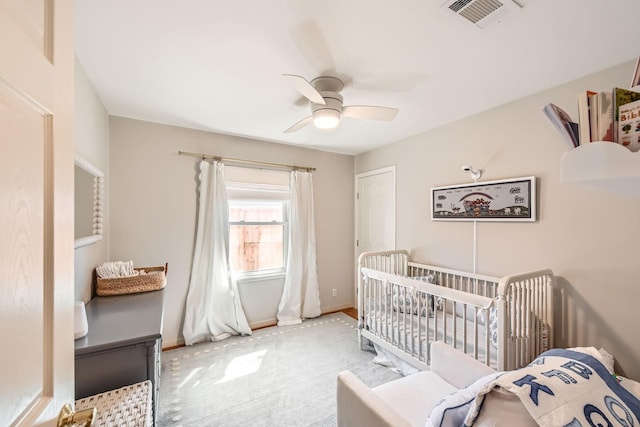 bedroom featuring baseboards, a ceiling fan, visible vents, a nursery area, and carpet