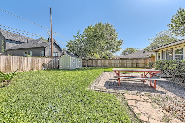 view of yard with a patio area, a fenced backyard, an outdoor structure, and a storage unit