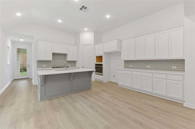 kitchen with visible vents, light countertops, white cabinetry, and stainless steel oven