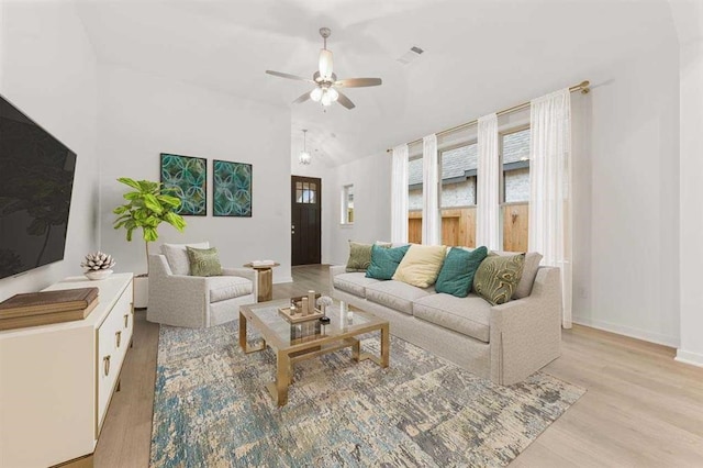 living room featuring plenty of natural light, light wood finished floors, a ceiling fan, and lofted ceiling
