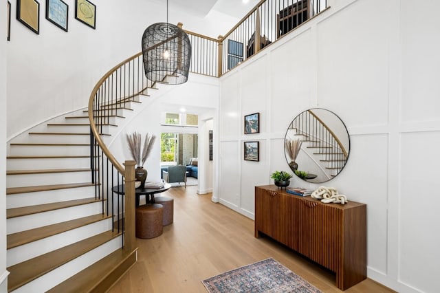 foyer entrance featuring a decorative wall, stairway, a high ceiling, and wood finished floors
