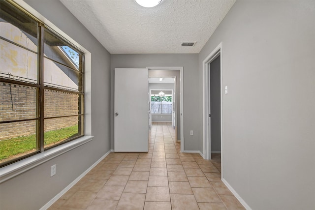6902 Desert Rose Ln, Houston, TX 77086 - corridor featuring light tile patterned floors, a textured ceiling, and baseboards