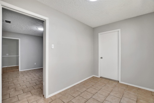 6902 Desert Rose Ln, Houston, TX 77086 - empty room featuring a textured ceiling, light tile patterned flooring, and baseboards
