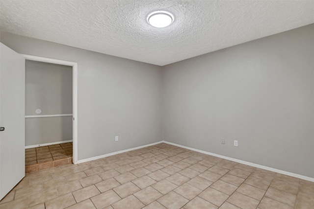 6902 Desert Rose Ln, Houston, TX 77086 - empty room with a textured ceiling, light tile patterned flooring, and baseboards