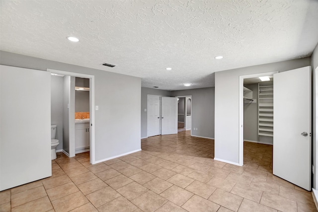 6902 Desert Rose Ln, Houston, TX 77086 - unfurnished bedroom with a walk in closet, baseboards, a textured ceiling, light tile patterned flooring, and recessed lighting