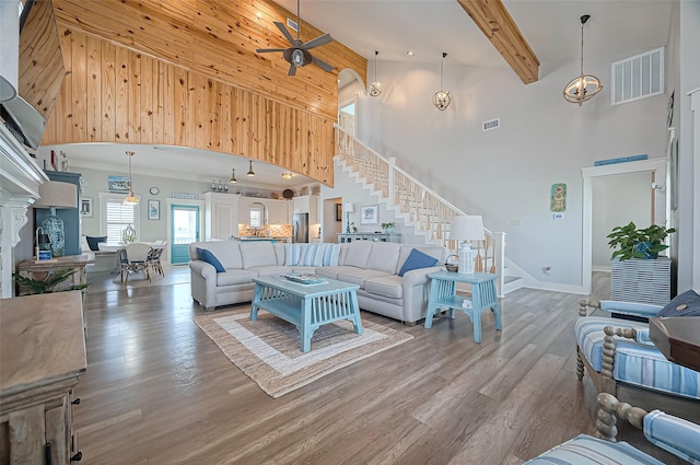 living area featuring high vaulted ceiling, stairway, visible vents, and wood finished floors