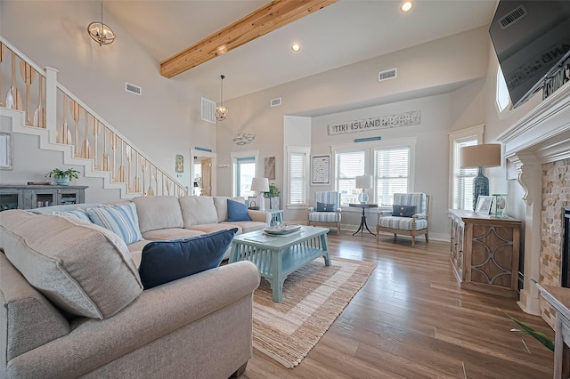 living room with a high ceiling, beam ceiling, and visible vents
