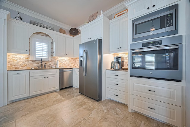 kitchen featuring white cabinets, a sink, ornamental molding, and appliances with stainless steel finishes
