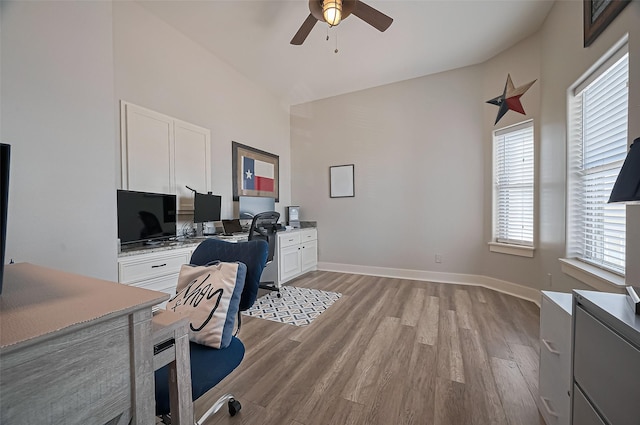 office area with high vaulted ceiling, light wood finished floors, baseboards, and a ceiling fan