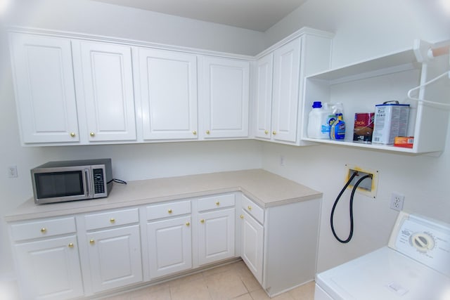 clothes washing area featuring light tile patterned floors, washer / dryer, and cabinet space