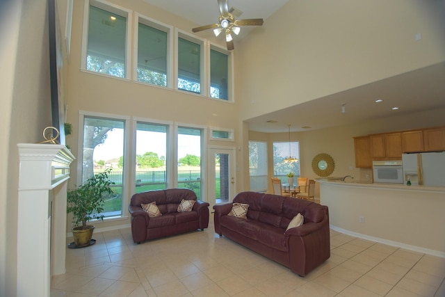 living area featuring light tile patterned floors, a towering ceiling, and ceiling fan