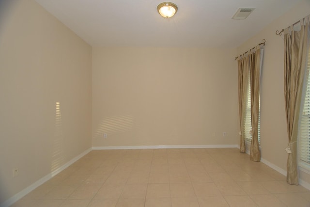 spare room featuring baseboards, visible vents, and light tile patterned floors