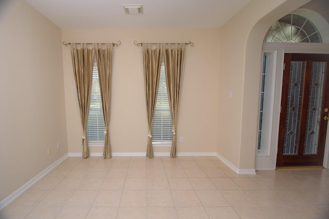 spare room featuring arched walkways, visible vents, and baseboards