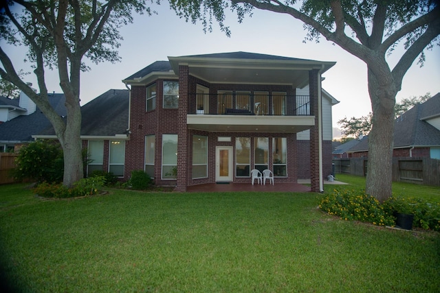 back of property with a patio, a balcony, a lawn, brick siding, and fence