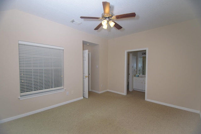 unfurnished bedroom featuring light colored carpet, ceiling fan, ensuite bathroom, baseboards, and visible vents