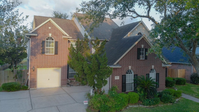traditional-style home with brick siding, fence, concrete driveway, and an attached garage