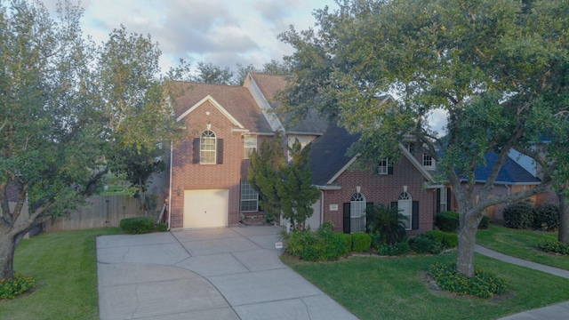 traditional-style house with driveway, fence, brick siding, a front lawn, and a garage
