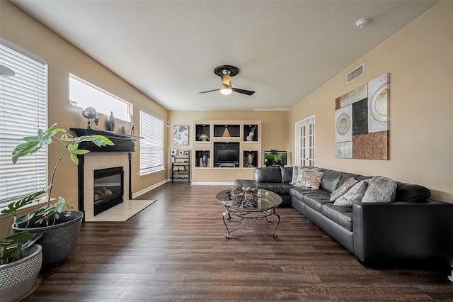living room with a fireplace, a ceiling fan, wood finished floors, and visible vents