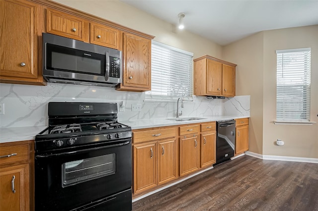 kitchen featuring dark wood-style flooring, a sink, light countertops, backsplash, and black appliances