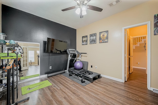 exercise room with a ceiling fan, baseboards, visible vents, and wood finished floors