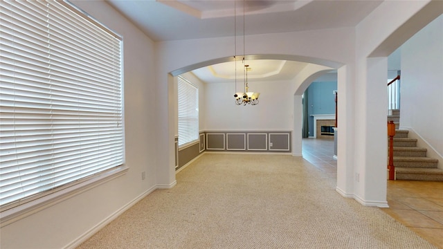 16410 Bluff Springs Dr, Houston, TX 77095 - unfurnished dining area with a notable chandelier, tile patterned flooring, stairway, a tray ceiling, and arched walkways