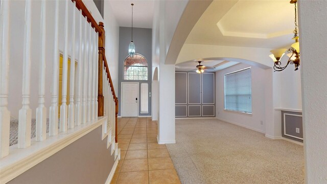 16410 Bluff Springs Dr, Houston, TX 77095 - entrance foyer featuring stairway, light tile patterned flooring, arched walkways, ceiling fan with notable chandelier, and light colored carpet