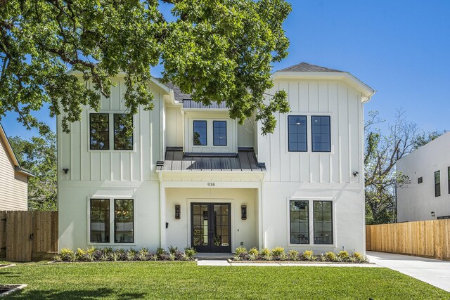 modern farmhouse with board and batten siding, french doors, a standing seam roof, and fence
